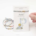 Pulsera detalle de Bautizo de cinta en varios estampados con cruz de nácar y bolas doradas. Incluye tarjeta de agradecimiento.